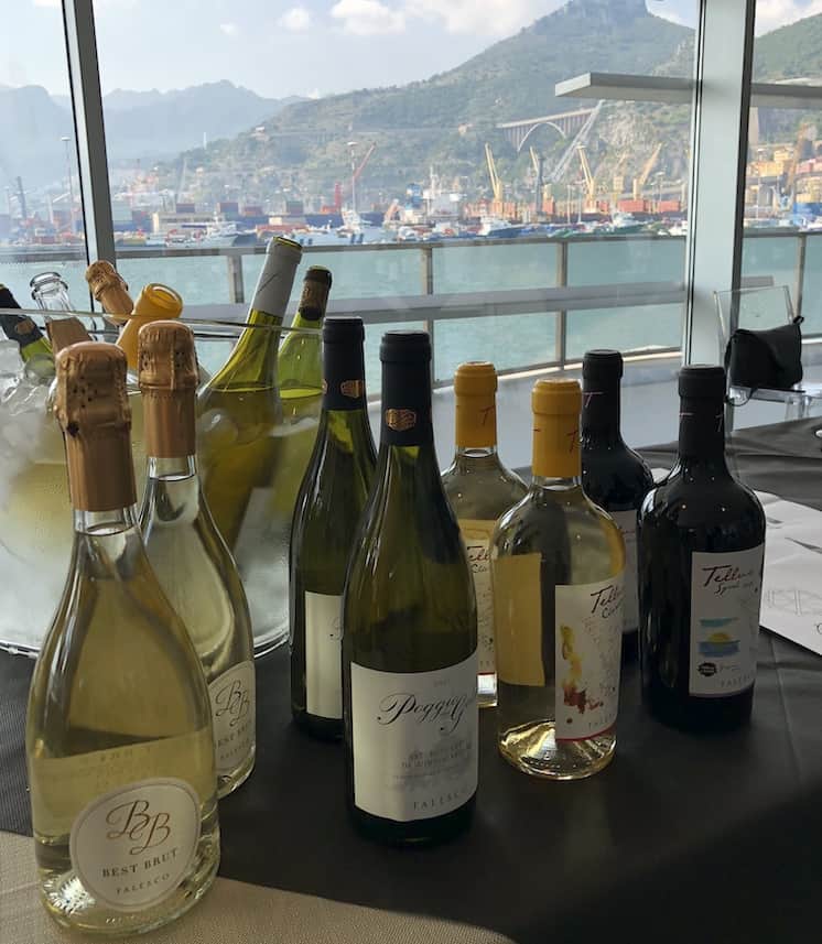 Bottiglie di vino ad In Vino civitas sullo sfondo del porto di Salerno